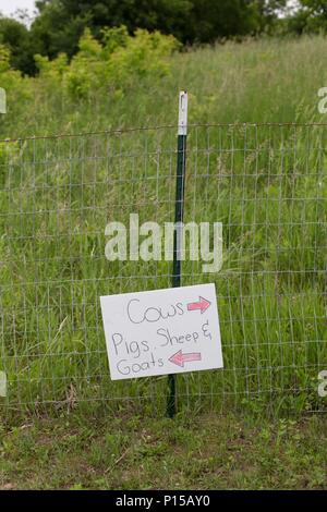 Un signe sur une clôture qui pointe vers différents types d'animaux de ferme. Banque D'Images