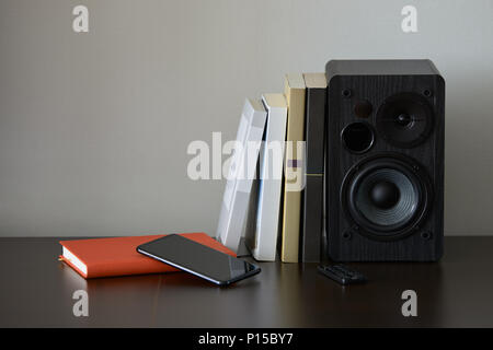 Bibliothèque avec livres, smartphone et contrôleur à distance sur un meuble TV Banque D'Images