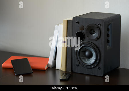 Bibliothèque avec livres, smartphone et contrôleur à distance sur un meuble TV Banque D'Images