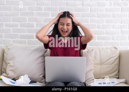 Asian woman freelancer crier avec le stress de l'émotion tout en travaillant avec un ordinateur portable et des formalités administratives de canapé dans la salle de séjour en chambre.travailler à home concept Banque D'Images