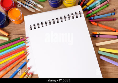 Blanc Blanc plié sur une école de l'ordinateur portable bureau avec différentes peintures, crayons et stylos. Banque D'Images
