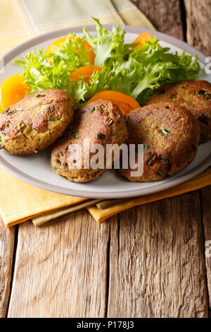 Galettes de thon aux herbes et salade de légumes frais sur une plaque verticale sur la table. Banque D'Images