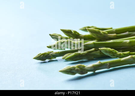 Asperges vertes biologiques sains prêts à cuire sur fond bleu Banque D'Images