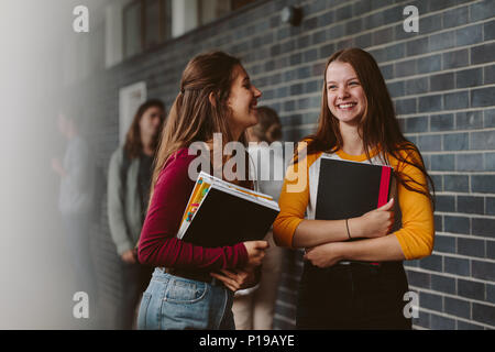 Portrait of smiling girls walking through high school corridor après leur classe. Deux étudiants du collège féminin après lecture. Banque D'Images