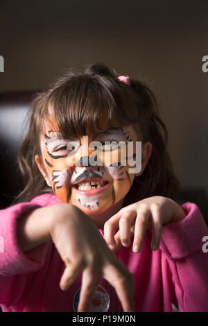Petite fille avec tiger tiger imitant la peinture face à la caméra de growl Banque D'Images