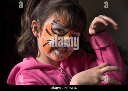 Petite fille avec tiger tiger imitant la peinture face à la caméra de growl Banque D'Images