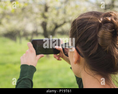Jeune femme de prendre une photo de la vue lors d'une randonnée dans un parc national avec un téléphone intelligent Banque D'Images