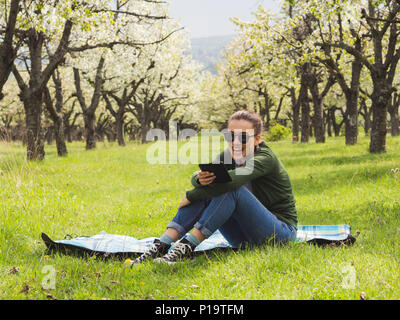 Young attractive woman reading on son ebook à l'extérieur et de rire Banque D'Images