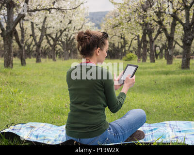 Vue arrière d'une jeune femme à l'extérieur la lecture sur son ebook Banque D'Images