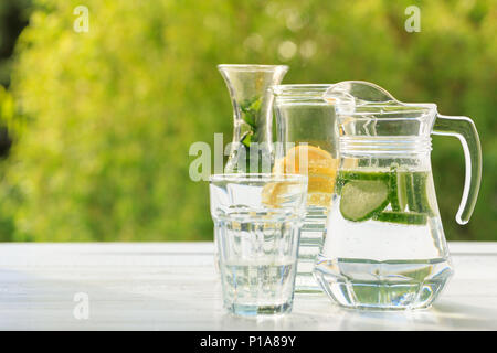 Trois variantes de limonade maison au citron, concombre et menthe. Dans pichets et limonade carafe sur jardin. Banque D'Images