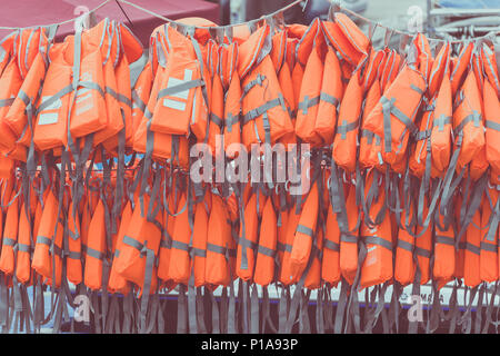 Orange nouveau gilet sport pour les eaux sont suspendus sur le port. Banque D'Images