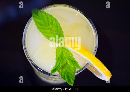 Verre de limonade verre avec les tranches de citron et menthe sur fond noir. En vue de dessus Banque D'Images