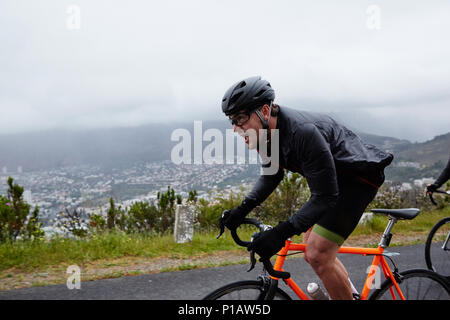 Cycliste homme déterminé à vélo sur route pluvieuse Banque D'Images