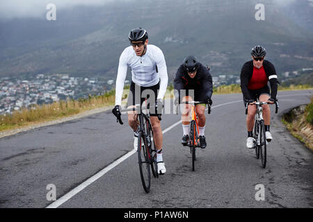 Les cyclistes masculins dédié à vélo sur route en montée Banque D'Images