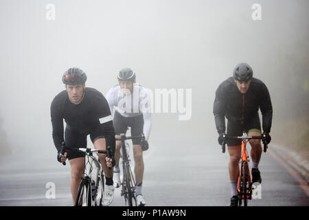 Les cyclistes masculins dédié à vélo sur route pluvieuse Banque D'Images