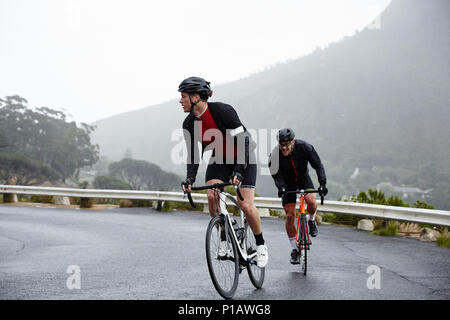 Les cyclistes masculins dédié à vélo sur route mouillée Banque D'Images