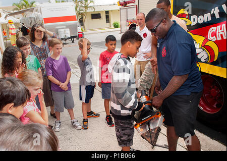 Le sergent de l'US Air Force. Demarcus Oliver, 18e Escadron de génie civile, pompiers montre aux enfants l'équipement de lutte contre les incendies durant la semaine de prévention des incendies le 5 octobre 2016, à Kadena Air Base, au Japon. Durant la semaine de prévention des incendies, les pompiers de la SCÉ 18 apprendre aux enfants Conseils de sécurité-incendie, comment vérifier les avertisseurs de fumée et de couronner le tout par un défilé dans les domaines du logement. (U.S. Air Force photo par un membre de la 1re classe Corey M. Pettis) Banque D'Images