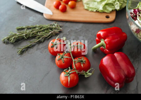 Gros plan d'une table de cuisine avec tomtoes, capsicum et planche à découper Banque D'Images