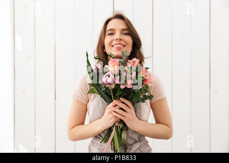 Beaux jeunes fleuriste heureux femme debout avec des fleurs en atelier. Banque D'Images