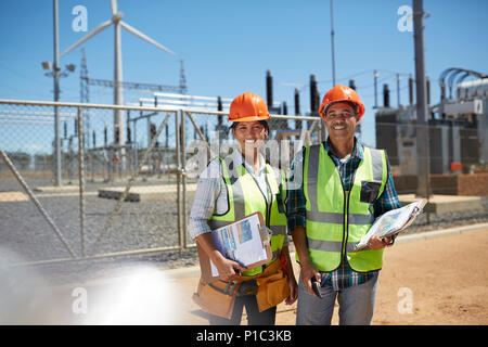 Portrait souriant, confiant d'ingénieurs avec les presse-papiers au power plant Banque D'Images
