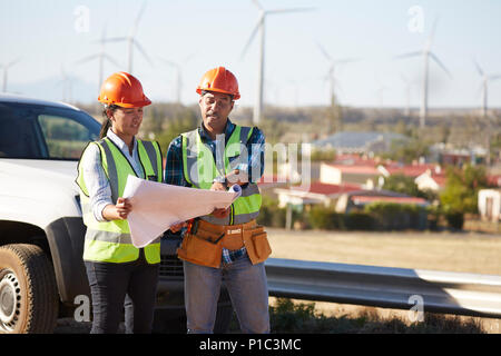 L'examen des plans d'ingénieurs près de ferme éolienne Banque D'Images