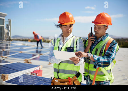 Les ingénieurs utilisant walkie-talkie et tablette numérique à solar power plant Banque D'Images