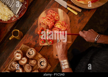 Vue aérienne woman slicing pizza à la tomate fraîche Banque D'Images