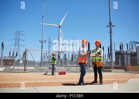 Les ingénieurs utilisant digital tablet at sunny wind turbine power plant Banque D'Images