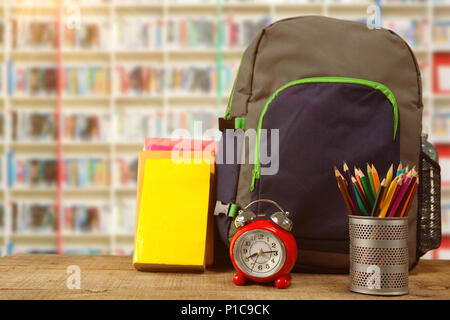 Image composite de fournitures scolaires par réveil sur table en bois Banque D'Images