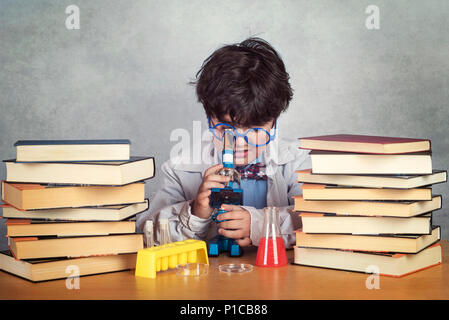 Garçon fait des expériences scientifiques sur fond gris Banque D'Images