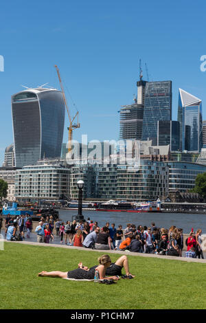 Londres, Royaume-Uni. 11 Juin, 2018. Météo britannique. La température atteint 24 degrés dans le soleil d'été à London Bridge dans la ville de Londres. Les employés de bureau et les touristes profitant de la chaleur du soleil en prenant leurs pauses de midi par la Tamise avec une vue sur la ville au-delà. L'iconic London city skylin sert de toile de fond pour les centaines de personnes profitant de la température chaude seaonal dans la capitale. Crédit : Steve Hawkins Photography/Alamy Live News Banque D'Images