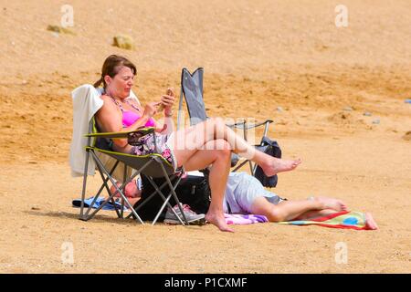 West Bay, Dorset, UK. 12 juin 2018. Météo britannique. Le soleil sur la plage, profiter de la chaleur du soleil voilé à la station balnéaire de West Bay, dans le Dorset. Crédit photo : Graham Hunt/Alamy Live News Banque D'Images