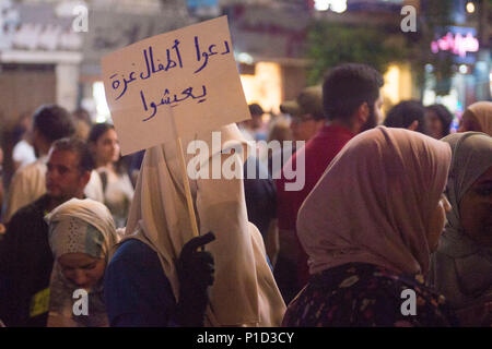 Une femme porte un signe que la foule marche dans la rue lors de manifestations contre Mahmoud Abass. Les Palestiniens se sont rassemblés à la place Al-Manara à mars en signe de protestation de Mahmoud Abass et l'Autorité palestinienne. Un groupe de partisans pro-Abass s'brièvement avec les manifestants, cependant la marche pacifique est resté après. Banque D'Images