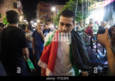 Un manifestant portant le drapeau palestinien comme une cape se joint aux manifestations contre Mahmoud Abass. Les Palestiniens se sont rassemblés à la place Al-Manara à mars en signe de protestation de Mahmoud Abass et l'Autorité palestinienne. Un groupe de partisans pro-Abass s'brièvement avec les manifestants, cependant la marche pacifique est resté après. Banque D'Images