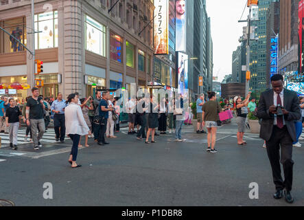 Les visiteurs de Times Square à New York jusqu'à la photographie généralement échoué Manhattanhenge coucher du soleil, l'horizon couvert de nuages, le mardi 29 mai 2018. Deux fois par an, cette année le soleil s'aligne au coucher du soleil avec la grille de la ville, l'éclairage des deux côtés de la rue et dans le milieu de la route. L'événement, le nom inventé par Neil deGrasse Tyson du Planétarium Hayden, a lieu 22 jours avant et 21 jours après le solstice d'été à cause de l'angle de 30 degrés de la grille de la ville, il n'est pas exactement à l'est-ouest-nord-sud. (Â© Richard B. Levine Banque D'Images