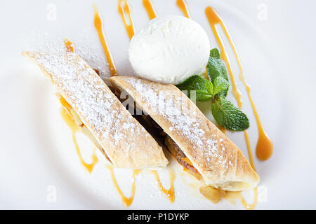 Strudel aux pommes avec de la crème glacée, saupoudrés de sucre glace et garnir de menthe Banque D'Images