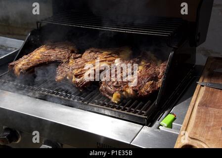 Barbecue : trois grandes coupes de boeuf français (Côte de boeuf à l'os) sur un barbecue à gaz Banque D'Images