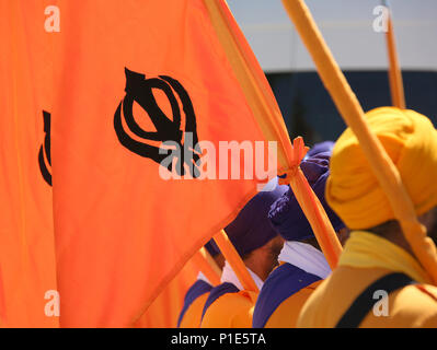 Drapeau orange avec symbole de la religion Sikh appelé KHANDA constitué par deux cimeterres et les hommes avec des turbans Banque D'Images