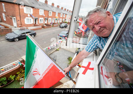 Gerry Sloan est suspendu à la fenêtre de sa chambre à coucher pour démêler le drapeau iranien à l'extérieur de son domicile à Whiterock jardins dans l'Ouest de Belfast comme lui et d'autres résidents ont pris la fièvre de la Coupe du monde pour créer un tirage et recueillir des fonds pour une fête dans la rue le jour de la finale de la Coupe du monde. Banque D'Images