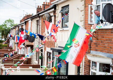 Gerry Sloan est suspendu à la fenêtre de sa chambre à coucher pour démêler le drapeau iranien à l'extérieur de son domicile à Whiterock jardins dans l'Ouest de Belfast comme lui et d'autres résidents ont pris la fièvre de la Coupe du monde pour créer un tirage et recueillir des fonds pour une fête dans la rue le jour de la finale de la Coupe du monde. Banque D'Images