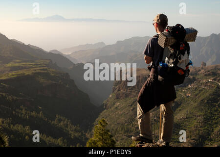 Randonneur donne sur le pays montagneux de la Grande Canarie vers le volcan du Teide, Gran Canaria, Îles Canaries, Espagne Banque D'Images