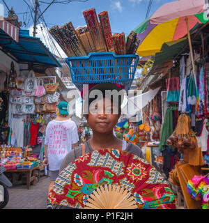 Un balinesian girl selling décoré main fans à partir d'un panier sur la tête, dans le marché d'Ubud, Bali, Indonésie, Banque D'Images