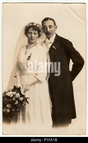 LIBEREC (REICHENBERG), RÉPUBLIQUE TCHÉCOSLOVAQUE - VERS 1920s : photo d'époque des jeunes mariés avec bouquet de mariage. La mariée porte l'adresse du voile de mariage. Le marié porte des vêtements chic, un noeud papillon blanc. Portrait de studio antique en noir et blanc. Ancienne photo, 1920s. Banque D'Images