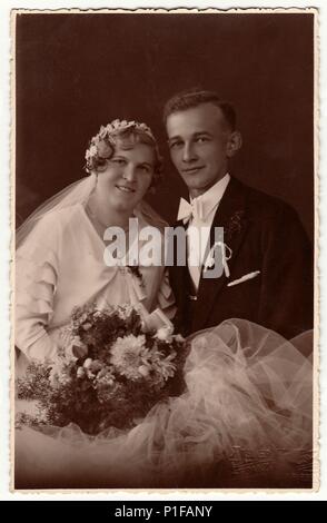 LIBEREC (REICHENBERG), RÉPUBLIQUE TCHÉCOSLOVAQUE - VERS 1940s : photo d'époque des jeunes mariés avec bouquet de mariage. La mariée porte l'adresse du voile de mariage. Le marié porte des vêtements chic, un noeud papillon blanc. Ancienne photo en noir et blanc. Portrait de studio antique. 1940s Banque D'Images