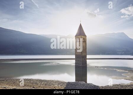 Vieux clocher de l'église dans l'eau au coucher du soleil. Lac de Resia (Lago di Resia ou Reschensee) dans le Tyrol du Sud, Italie. Banque D'Images