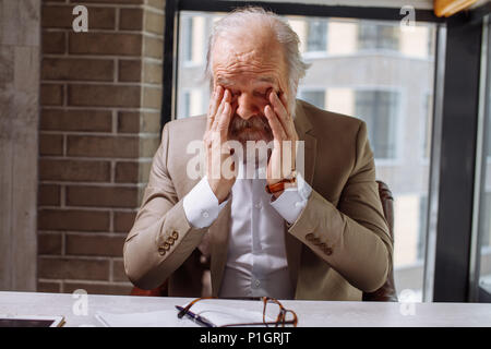 Closeup portrait d'un homme âgé se frotter les yeux après le dur travail Banque D'Images