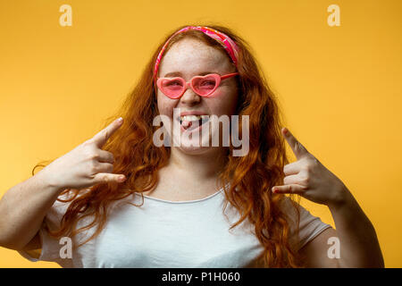 Portrait of beautiful smiling redhead girl wearing big fashion lunettes roses Banque D'Images