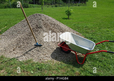 Pelle brouette Construction sur une pile d'une roche de gravier dans un jardin. Banque D'Images