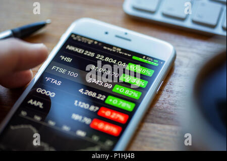 BATH, Royaume-Uni - Juin 11, 2018 : Un Apple iPhone 6 sur un bureau afficher les cours de la bourse en utilisant les actions Apple app. Une main humaine suspendu au-dessus du FT Banque D'Images