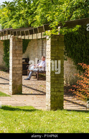 Jardins de l'abbaye de Malmesbury, un visiteur se trouve dans le soleil et des silences, Wiltshire, UK Banque D'Images